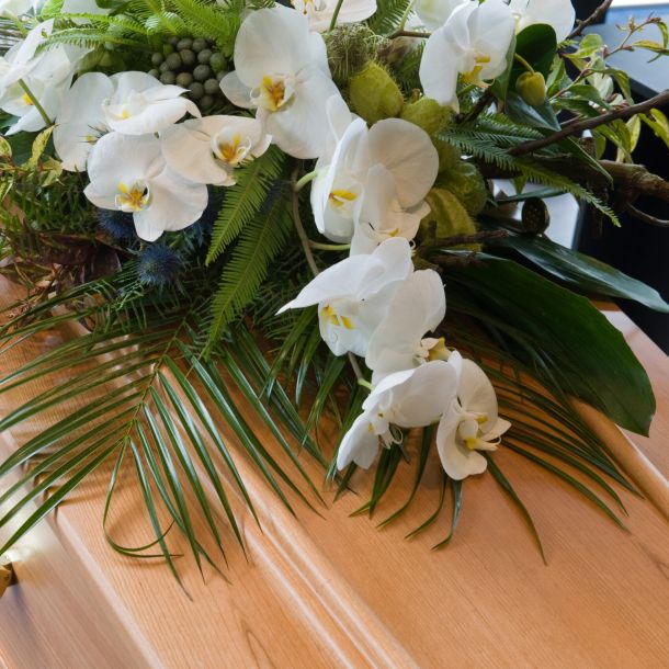 Una bara con una composizione floreale in un obitorio