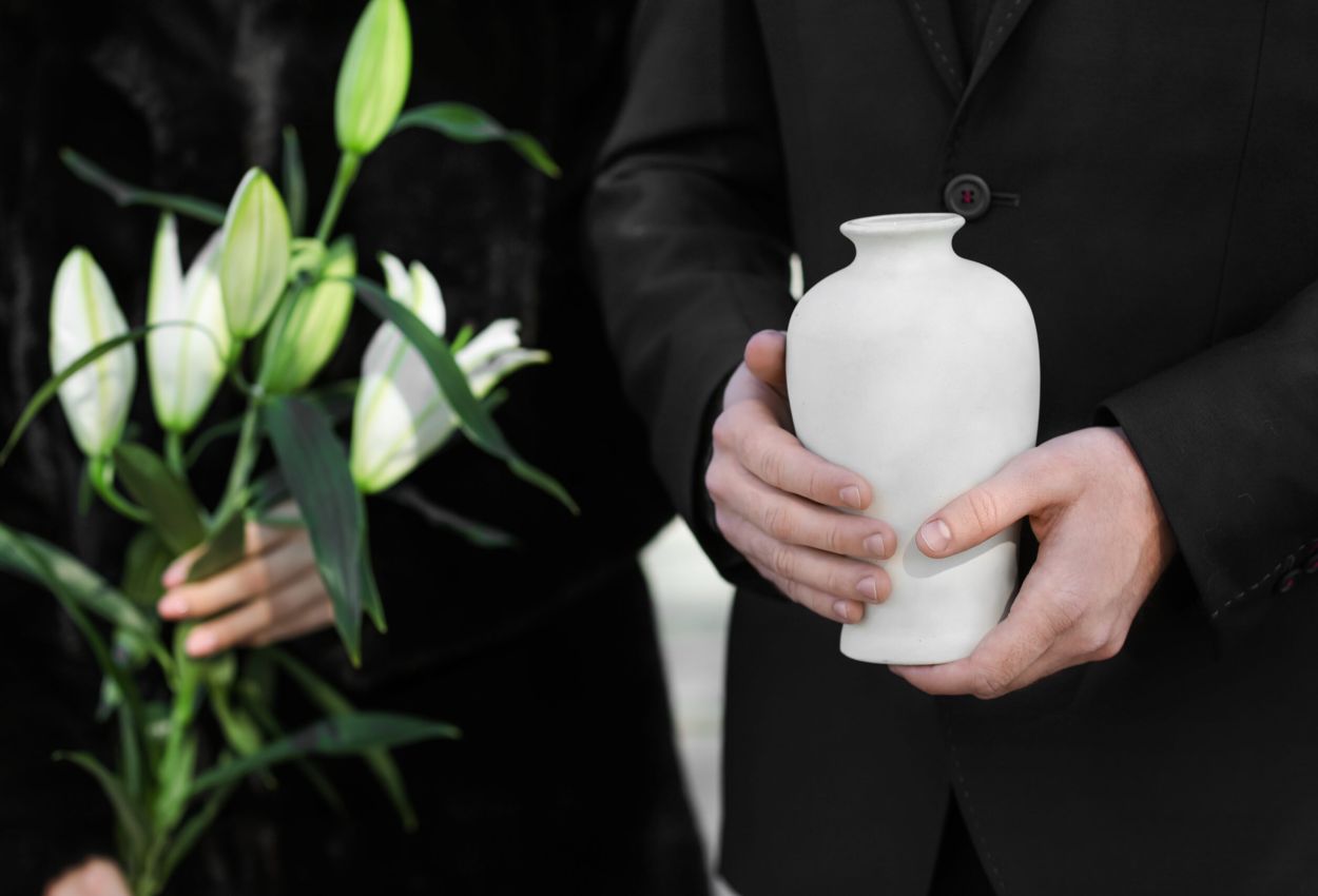 Urna bianca nelle mani con fiori bianche